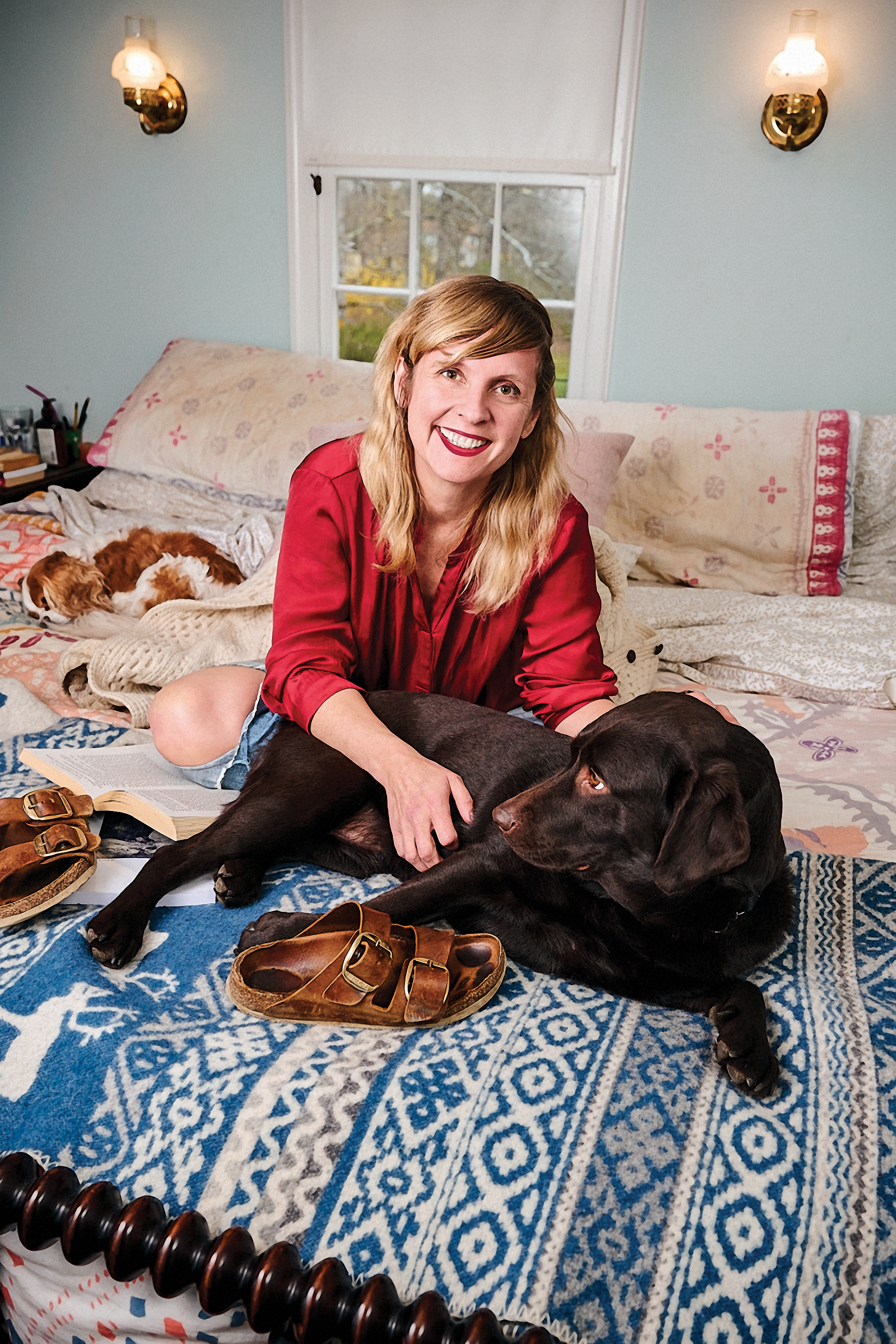 Leigh Newman on a bed with two dogs