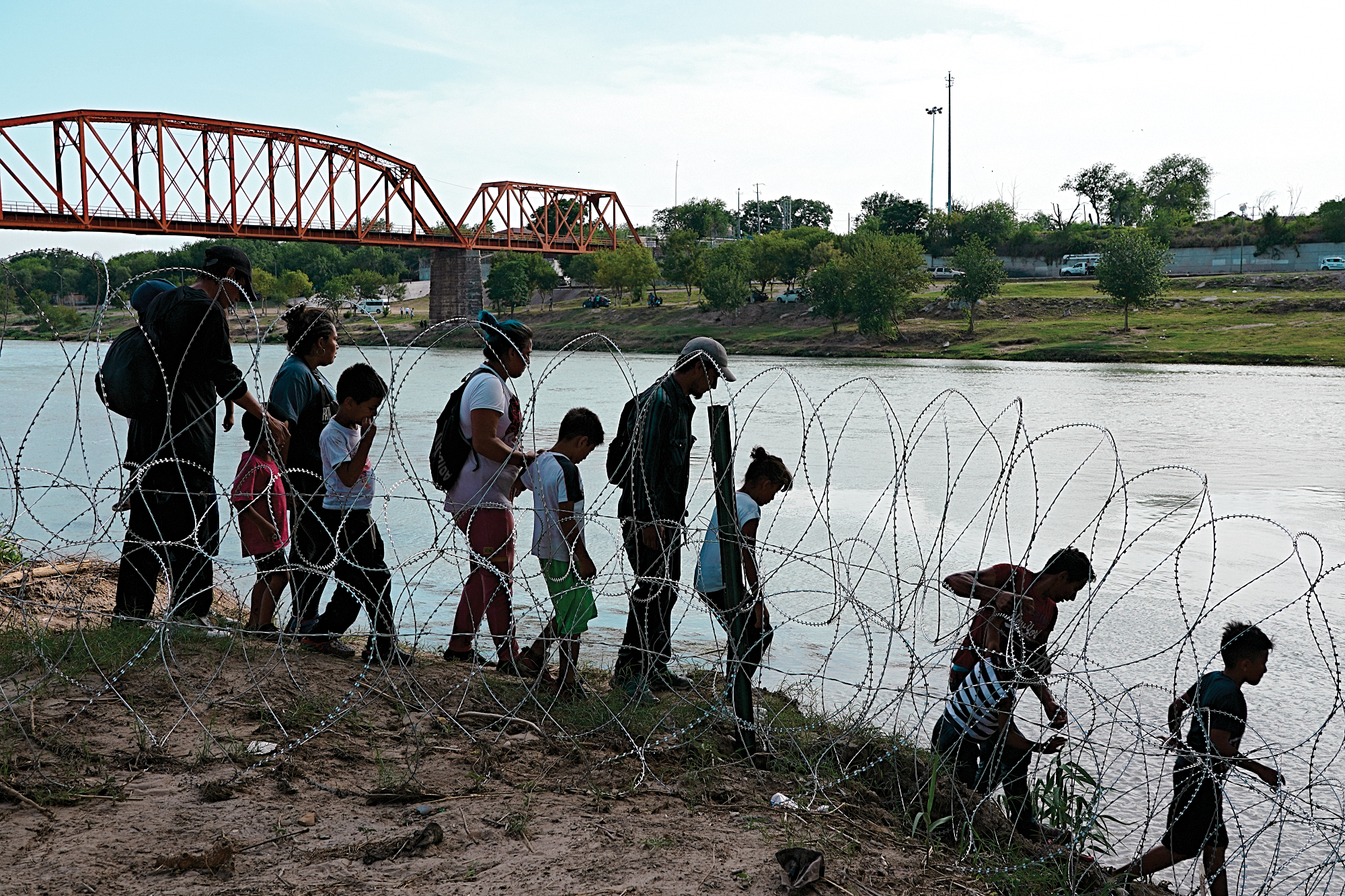 People crossing through wire at a river