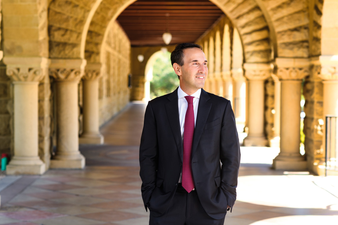 Jonathan Levin standing in the Quad in front of column archways