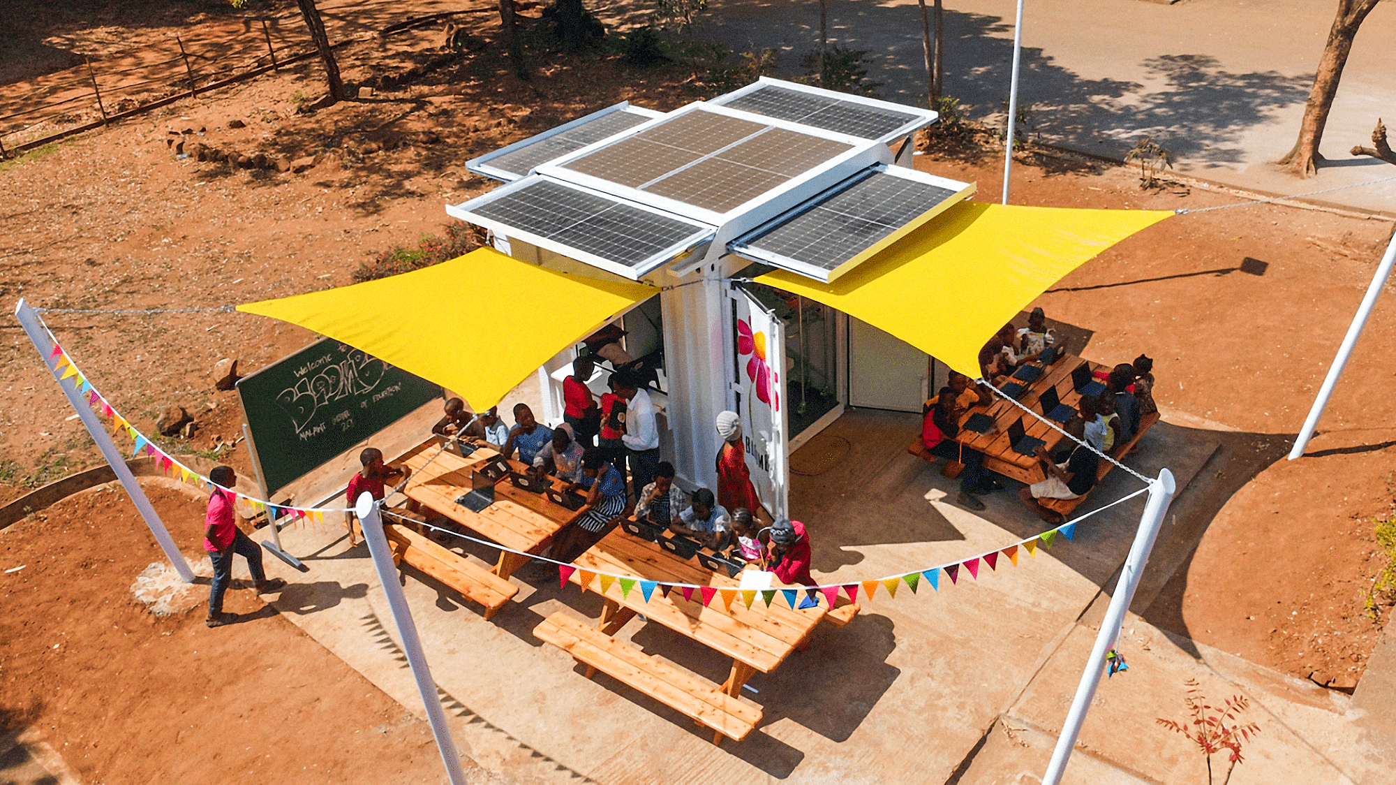 People sitting in picnic tables outside of a Bloombox