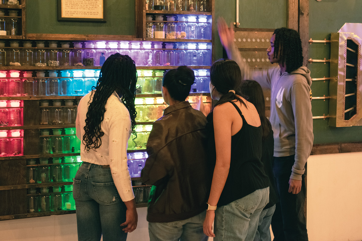 Five people standing in front of lighted jars in a the Edison room.