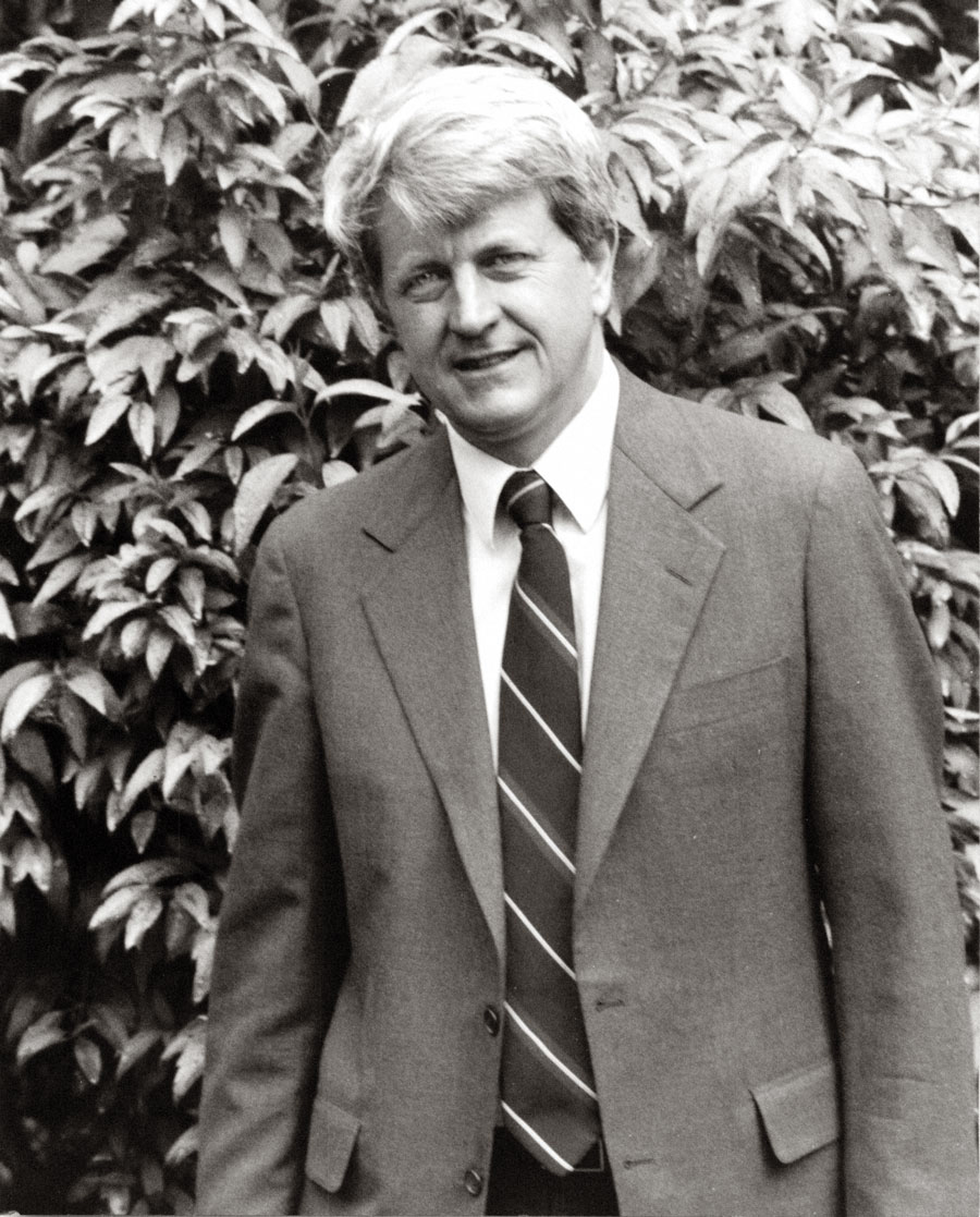 Portrait of Thomas Neff in a suit and tie in front of shrubbery