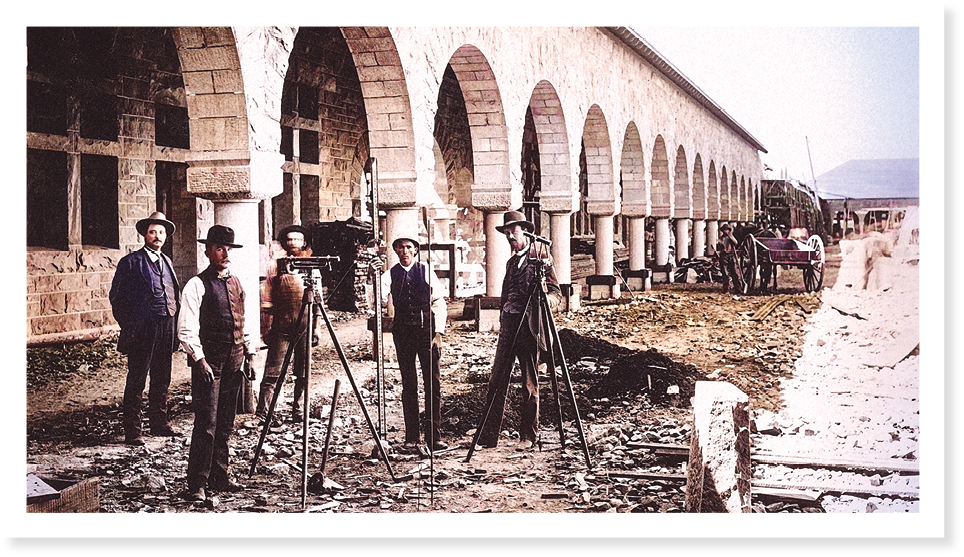 Old photograph of the Main Quad being built. Five men in front of building.